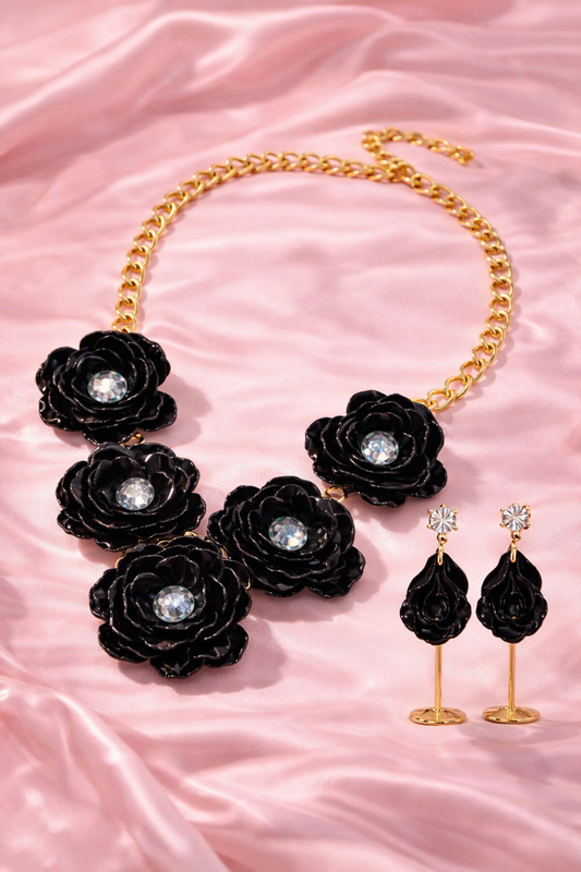 Black rose flower jewelry set featuring a bold gold tone necklace and matching drop earrings.